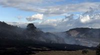 Labores de control y refrigeración de bomberos en una zona afectada por incendios forestales en Cundinamarca.