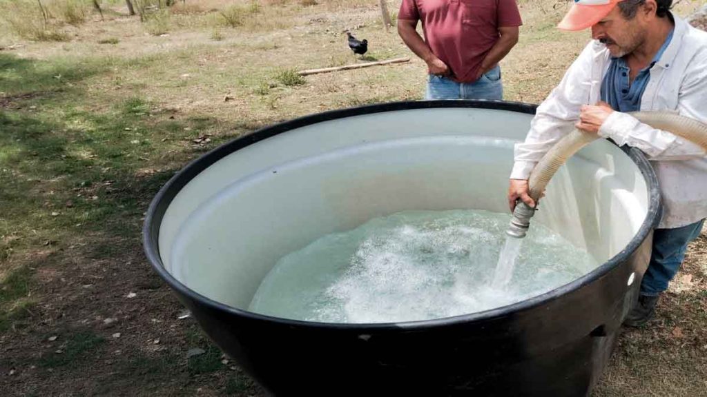 Operarios de Empresas Públicas de Cundinamarca distribuyen agua potable mediante carrotanques a familias afectadas por la temporada seca.